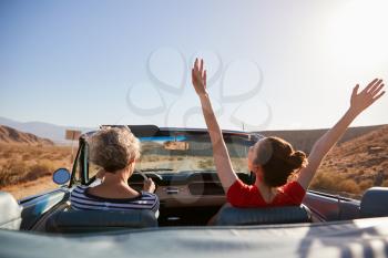 Mum driving car, daughter with hands in the air, back view