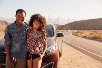 Young black couple standing on desert roadside by their car
