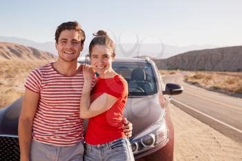 Young white couple standing on desert roadside by car
