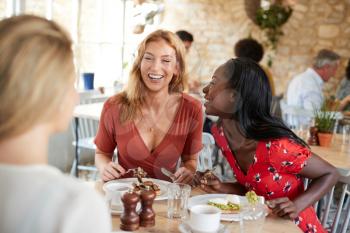 Three female friends talking over brunch at a cafe, close up