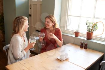Two young female friends talking over drinks in a pub