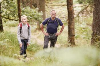 Grandfather and grandson taking a break while hiking in a forest, selective focus