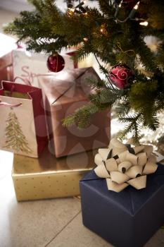 Gifts arranged under a decorated Christmas tree, close up