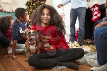 Portrait Of Girl With Pet French Bulldog Celebrating Family Christmas At Home Together