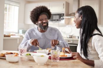 Happy black couple enjoying eating their Sunday dinner together at home, close up