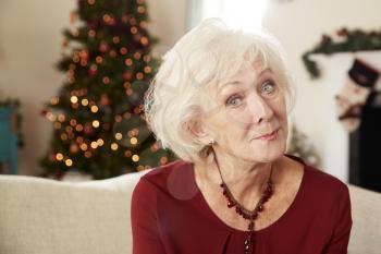 Portrait Of Senior Woman Sitting On Sofa In Lounge At Home On Christmas Day