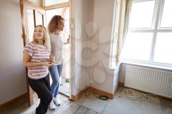 Excited Female Couple Opening Front Door Of New Home