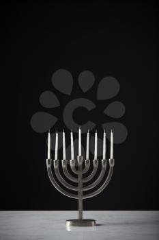 Metal Hanukkah Menorah With Unlit Candles On Marble Surface Against Black Studio Background