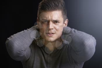 Portrait of angry young white man with hands behind his neck