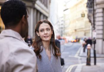 Millennial business colleagues standing on a street in London having a conversation, close up