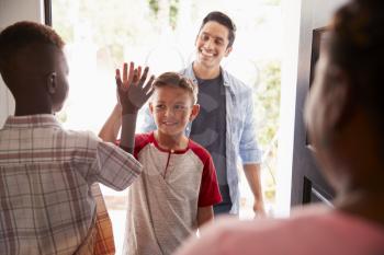 The two pre-teen boys high five in the open doorway, as dad drops his son off at his friends house