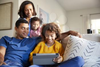 Young family spending time together using a tablet computer in their living room, front view