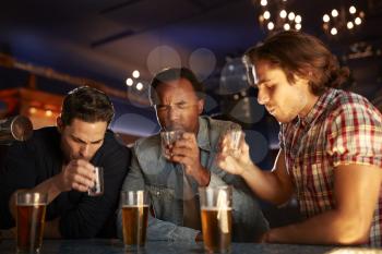 Group Of Male Friends Drinking Shots In Bar Together