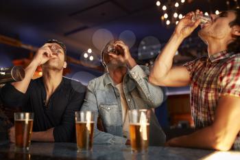 Group Of Male Friends Drinking Shots In Bar Together