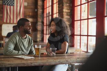 Young Couple Meeting In Sports Bar Enjoying Drink Before Game