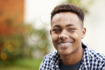 Young black man outdoors smiling to camera, close up, head and shoulders