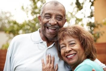 Senior husband and wife embracing, smiling to camera, close up