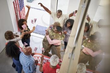 Young black male soldier welcomed home by three generation family, elevated view