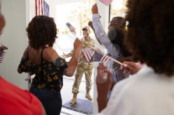 Millennial woman and family welcoming young black male soldier home, close up