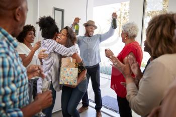 Millennial black couple arriving at a family party with gifts and champagne, close up