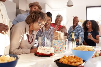 Middle aged black woman cutting cake during a three generation family birthday celebration,close up