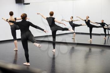 Female Students At Performing Arts School Rehearsing Ballet In Dance Studio Reflected In Mirror