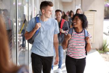 Group Of Smiling Male And Female College Students Walking In School Building Corridor