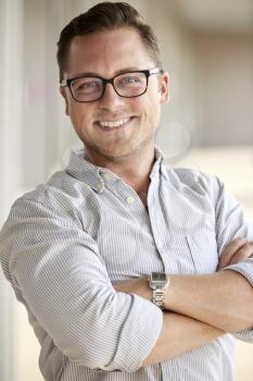 Portrait Of Smiling Male School Teacher Standing In Corridor Of College Building