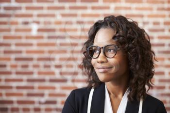 Smiling Businesswoman Wearing Glasses Standing Against Brick Wall In Modern Office