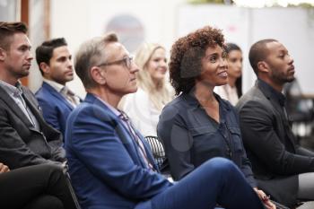 Group Of Businessmen And Businesswomen Listening To Presentation At Conference