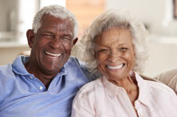 Portrait Of Loving Senior Couple Sitting On Sofa At Home Together