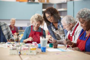 Group Of Retired Seniors Attending Art Class In Community Centre With Teacher