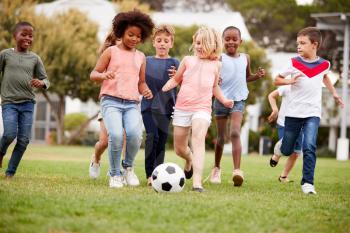 Group Of Children Playing Football With Friends In Park