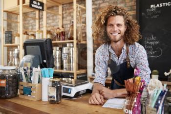 Portrait Of Male Owner Of Sustainable Plastic Free Grocery Store Behind Sales Desk