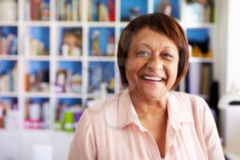 Portrait Of Smiling Mature Woman In Home Office By Bookcase