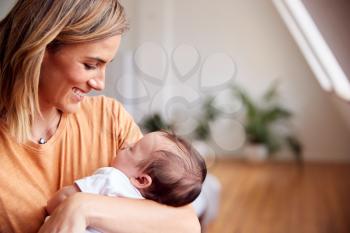 Loving Mother Holding Newborn Baby At Home In Loft Apartment