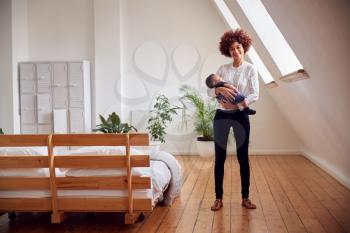 Portrait Of Loving Mother Holding Newborn Baby At Home In Loft Apartment