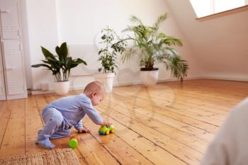 Baby Boy Playing With Toys On Floor At Home