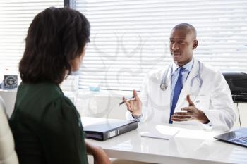 Female Patient In Consultation With Doctor Sitting At Desk In Office