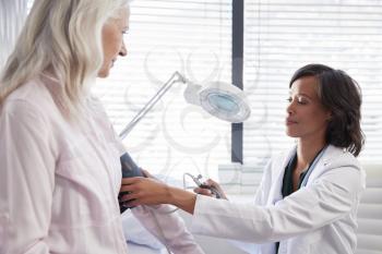 Woman Patient Having Blood Pressure Taken By Female Doctor In Office