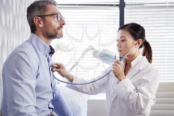 Mature Male Patient Having Medical Exam With Woman Doctor In Office
