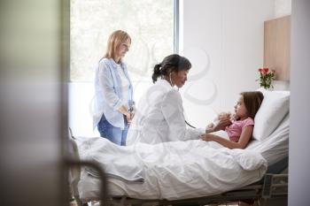 Female Doctor Visiting Mother And Daughter Lying In Bed In Hospital Ward