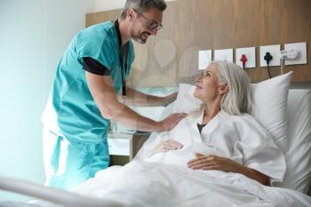Surgeon Visiting And Talking With Mature Female Patient In Hospital Bed
