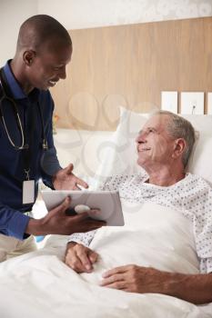 Doctor With Digital Tablet Visiting And Talking With Senior Male Patient In Hospital Bed