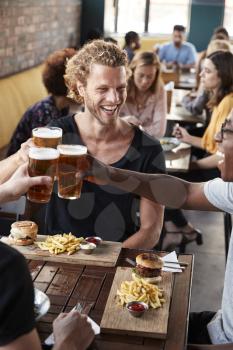 Three Young Male Friends Meeting For Drinks And Food Making A Toast In Restaurant