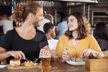 Couple On Date Meeting For Drinks And Food In Restaurant