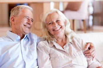 Happy senior white couple sitting at home embracing, front view, close up