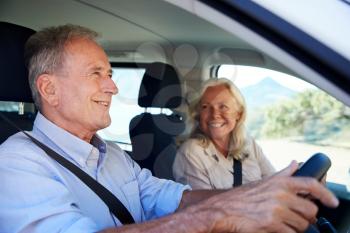 Senior white man driving car, his wife beside him in the front passenger seat, close up, side view