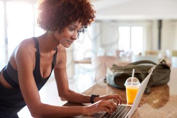 Millennial African American woman checking fitness app on laptop after workout, side view