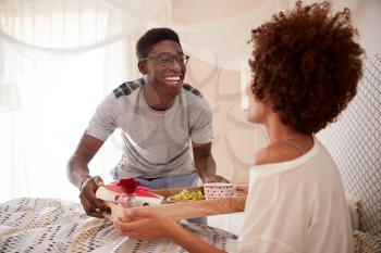 Millennial African American couple celebrating, man bringing his partner breakfast in bed, close up
